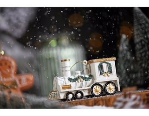 Detailed view of a white and gold miniature Christmas train on a snowy background