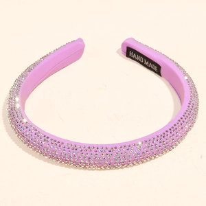 Detailed macro view of purple rhinestone headband featuring handmade label and satin fabric