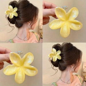 Macro details of a yellow resin plumeria hair claw clip with marble texture for updo hair