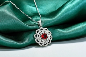 Gros plan d'un pendentif tournesol en rubis avec zircons sur un tissu en soie verte
