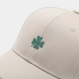 Close-up of green shamrock embroidery on a beige cotton twill baseball cap with fine stitching
