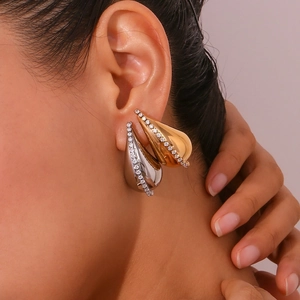 Close-up of elegant gold and silver teardrop earrings with pavé zircon on a model