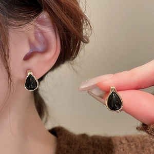 Detail of vintage teardrop earrings with black faux tiger eye stone and gold plating