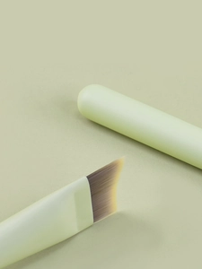Macro shot of mint green angled foundation brush with soft synthetic bristles for makeup