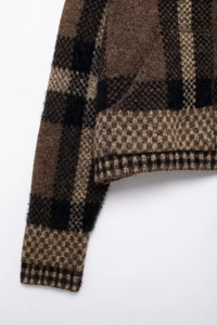 Dettaglio macro della trama in maglia a rombi e dell'orlo a coste sul cardigan
