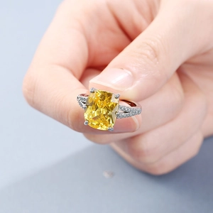 Silver ring featuring a large rectangular yellow gemstone and clear side stones