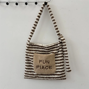 Détail d'un sac bandoulière en peluche rayé avec poche avant et broderie fine