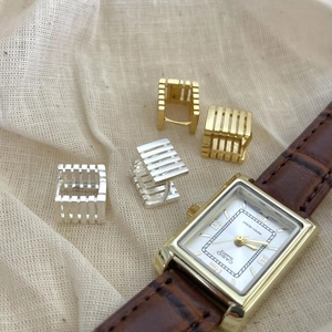 Detailed macro view of silver and gold square earrings with architectural fence pattern