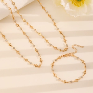 Close-up of gold double-layer necklace and bracelet set with heart charms and rhinestones