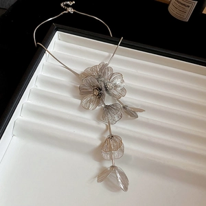 Detail of silver hollow flower pendant necklace on white display tray with elegant tassel
