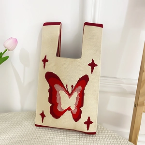 Close-up of knit tote bag with red butterfly patterns and star embroidery details