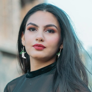 Green western cowboy boot earrings with zircon accents worn by a model in soft light