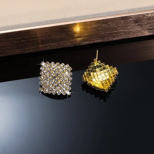 Macro view of geometric diamond stud earrings with golden textured back and clear zircons