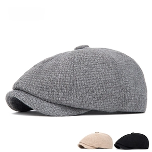 Detail showing grey, beige and black wool newsboy caps with textured knit pattern