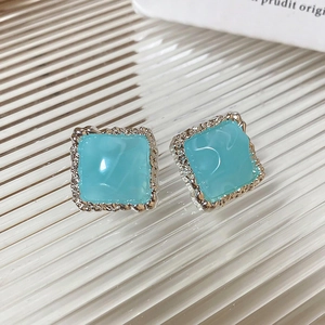 Détail de boucles d'oreilles carrées en résine bleu clair avec bords texturés argentés