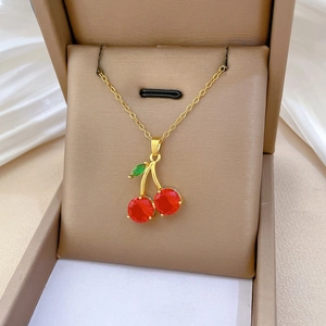 Détail d'un collier cerise avec cristaux rouges sur une chaîne dorée dans un écrin à bijoux