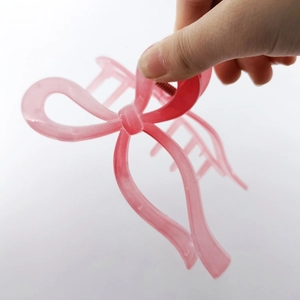 Pink ribbon bow hair claw clip made of translucent resin, hand-held size demonstration