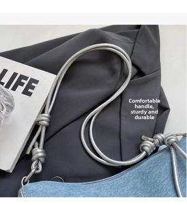 Detailed close-up of light blue denim hobo bag with stylish silver knotted shoulder strap