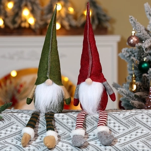 Detail of two Christmas gnomes with long striped legs and soft felt hats on table