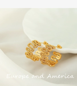 Detail of gold-plated wavy earrings with fine granular texture on white silk fabric