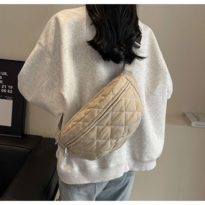 Close-up of khaki quilted crossbody chest bag with adjustable strap on a female model