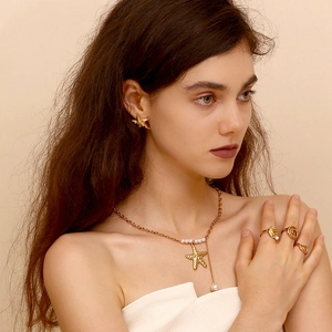 Detail of 18K gold starfish earrings and necklace with pearls worn by a model