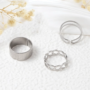 Three-piece set of silver titanium steel rings with minimalist designs on white silk background