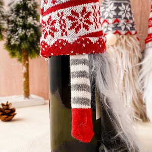 Close-up of a Christmas gnome wine bottle cover with red and white snowflake knit hat