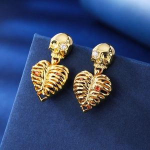 Gothic gold skull heart skeleton earrings with zircon insets on blue background