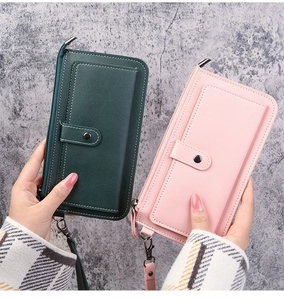 Detail of long multi-functional wallets in dark green and pink with wrist straps