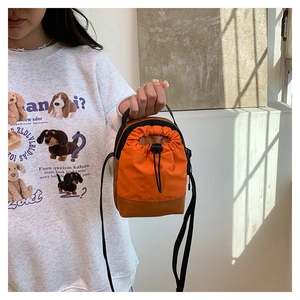 Detail of orange nylon and leather crossbody bag with drawstring closure and slim strap