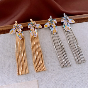 Macro detail of leaf-shaped enamel earrings with long metallic fringe in gold and silver