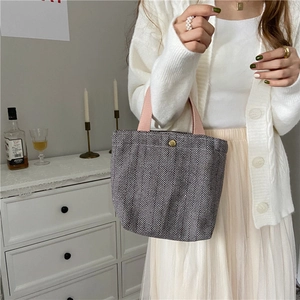 Detail of herringbone pattern tote bag with pink straps and golden snap button closure