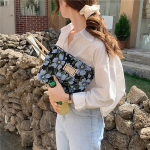 Close-up of floral jacquard fabric texture and leather label on retro underarm bag