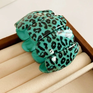 Gros plan d'un bracelet large à motif léopard turquoise rangé dans son écrin