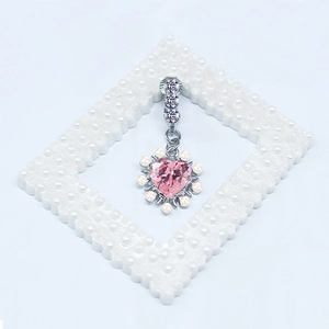 Détail d'un piercing de nombril cœur opale rose avec perles et accents argentés