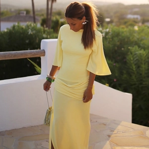 Detail of elegant yellow maxi dress showing loose ruffle sleeves and flowing draped fabric