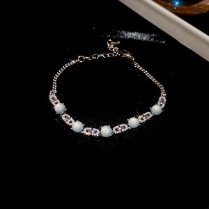 Vue détaillée d'un bracelet argenté avec des pierres bleues et un pendentif de lettre