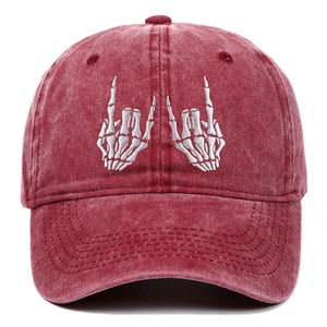 Macro detail of white skeleton hands embroidery on washed burgundy cotton baseball cap