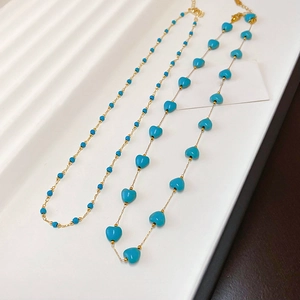 Detail of gold plated necklaces featuring turquoise blue round and heart-shaped beads