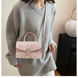 Détail du sac bandoulière rose brodé avec décor papillon 3D et poignée tissée élégante