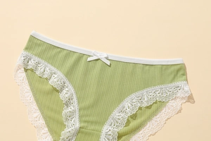 Close-up of light green ribbed fabric panties with white lace trim and bow detail