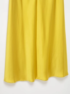 Détail du tissu satiné jaune vif montrant la texture lisse et la couture de l'ourlet