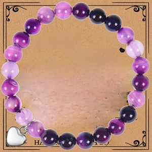 Détail du bracelet en pierres naturelles violettes avec breloque cœur sur carte cadeau