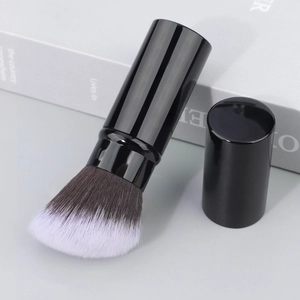 Close-up of portable flat-top foundation brush with soft synthetic bristles and protective cap