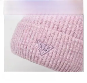 Close-up of pink knitted beanie with ribbed texture and purple letter embroidery detail
