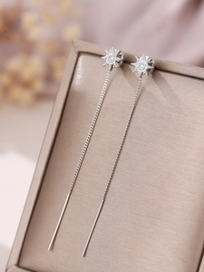 Macro view of silver star tassel earrings with zircons on a beige jewelry display box