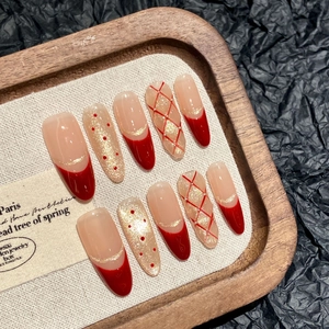 Red and gold festive press-on nails with French tips and glittery plaid patterns