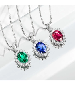 Close-up of oval sapphire, ruby, and emerald pendant necklaces on a white tiered stand