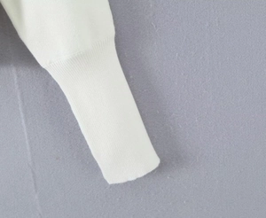 Detail der weißen Strickjacke mit feiner Rippenstruktur und hochwertiger Verarbeitung
